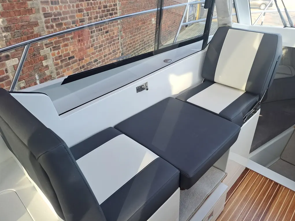 Luxury boat seating with black and white cushions, set against a textured brick wall, enhancing a nautical atmosphere.